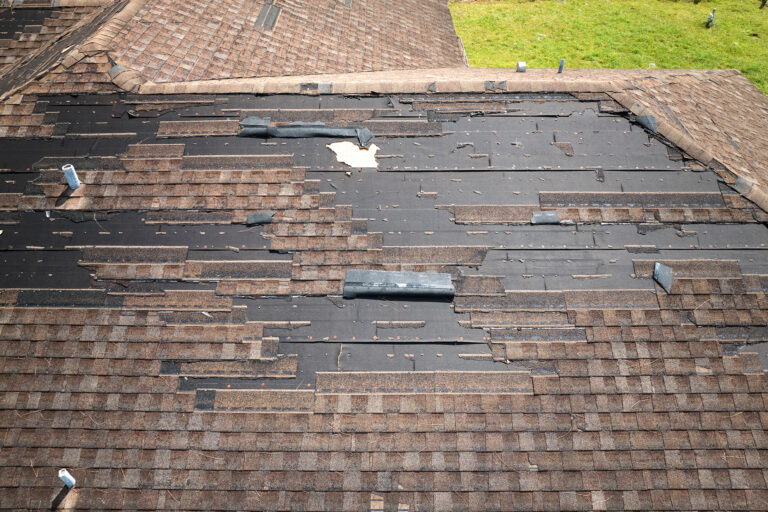 Wind damaged house roof with missing asphalt shingles after hurricane Ian in Florida. Repair of home rooftop concept.